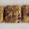 hree rectangular dog treats with a textured, golden-brown appearance and visible berries.