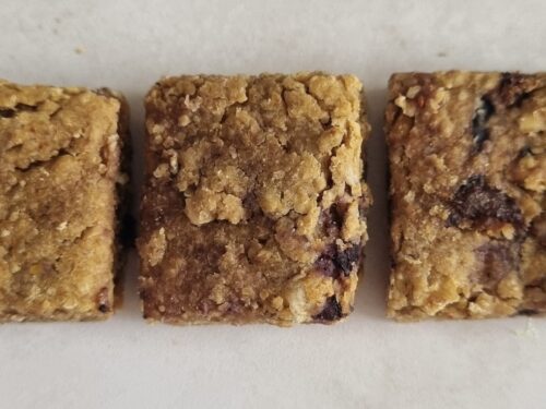 hree rectangular dog treats with a textured, golden-brown appearance and visible berries.