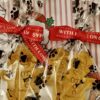 christmas-dog-treats-gingerbread-wrapped.jpg Gingerbread-person shaped dog treats wrapped in cellophane bags with red festive ribbon saying "with love" and paw print wrapping paper background