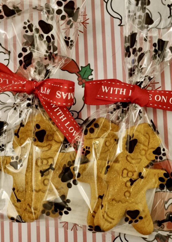 christmas-dog-treats-gingerbread-wrapped.jpg Gingerbread-person shaped dog treats wrapped in cellophane bags with red festive ribbon saying "with love" and paw print wrapping paper background