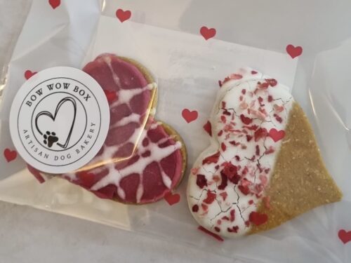 Close up of Valentine dog treats UK showing Love Bites heart cookies with pink drizzle and sprinkles from Bow Wow Box