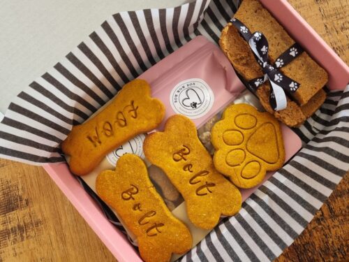 Bow Wow Box branded gift box with personalised "Bolt" and "Woof" bone-shaped dog treats, a paw-shaped biscuit and a ribbon-tied treat bar