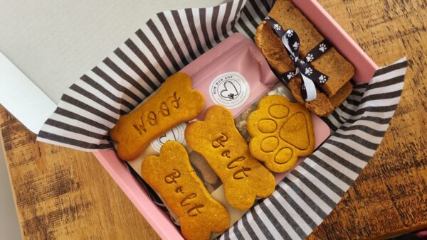 Bow Wow Box branded retail packaging Bow Wow Box branded gift box with personalised "Bolt" and "Woof" bone-shaped dog treats, a paw-shaped biscuit and a ribbon-tied treat bar