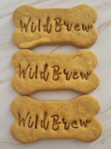 Three bone-shaped dog treats custom-branded with "WILDBREW" block lettering, a bespoke wholesale order from Bow Wow Box