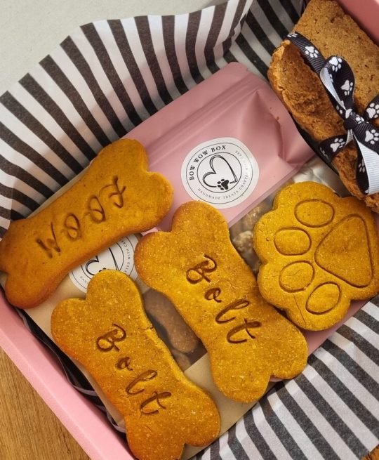 Bow Wow Box branded gift box with personalised "Bolt" and "Woof" bone-shaped dog treats, a paw-shaped biscuit and a ribbon-tied treat bar